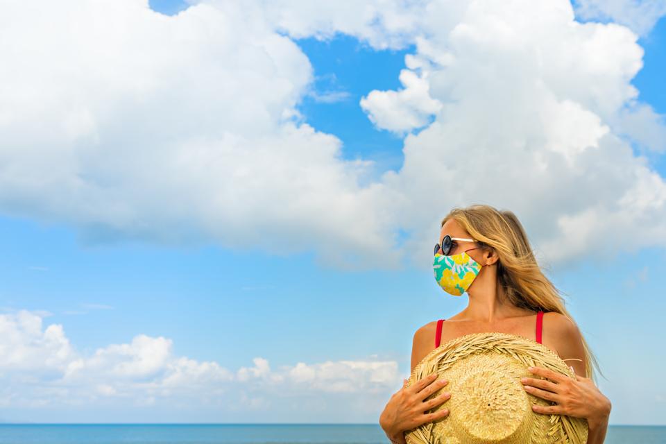 Young woman wearing sunglasses, face mask on tropical beach
