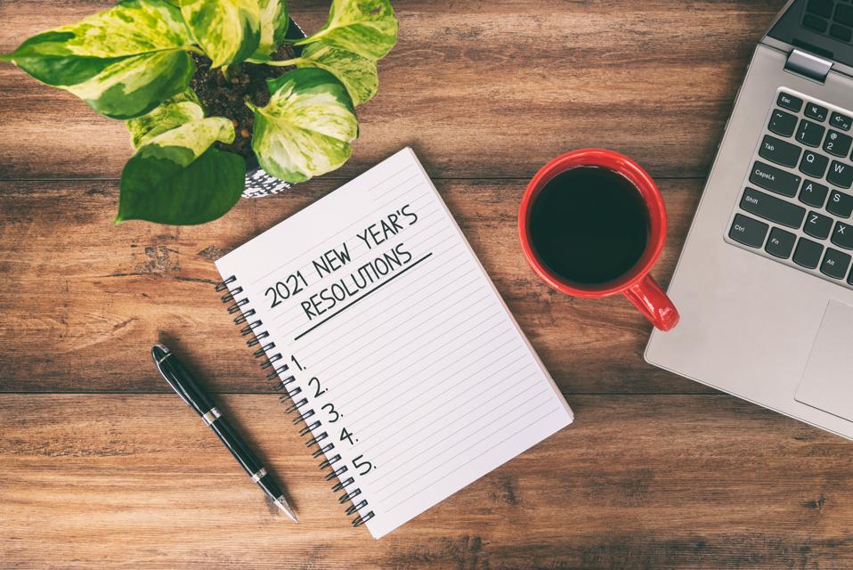 2021 New year's Resolutions Text Written on Notepad With Laptop and Cup of Coffee on Top of Wooden Desk