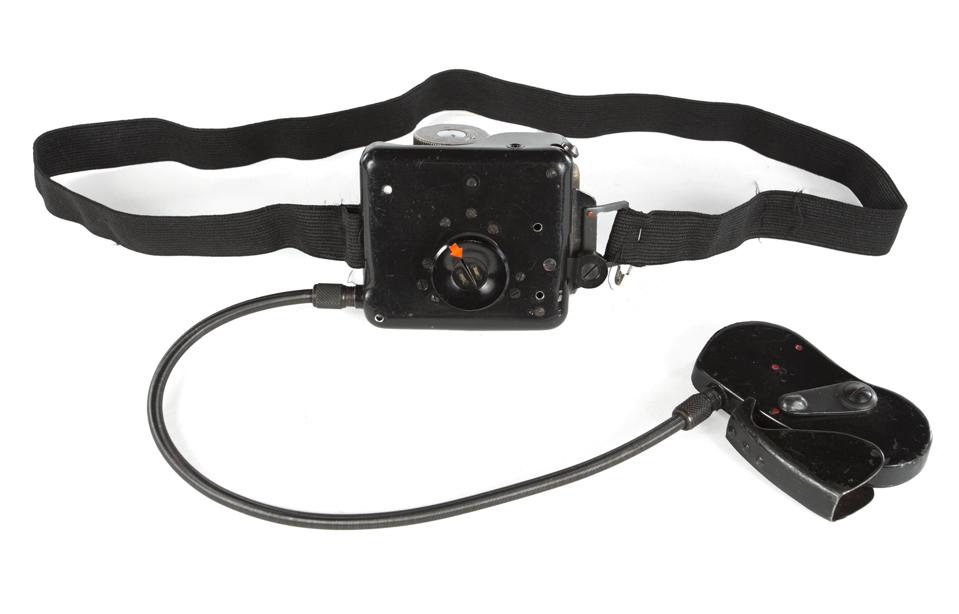 Kūno kamera su objektyvu, užmaskuota kaip sagos striukė.