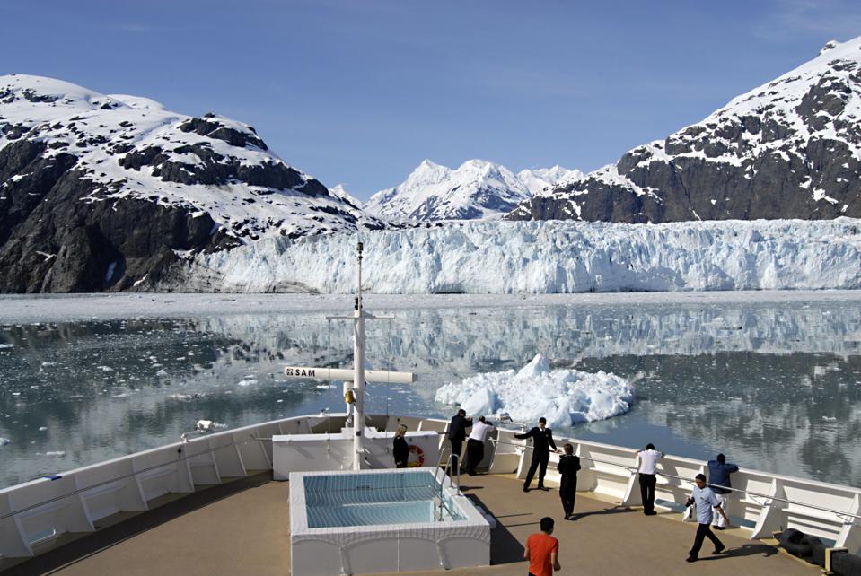 Tourists stand on the bow of a cruise ship to see Glacier Bay and the mountains in Alaska