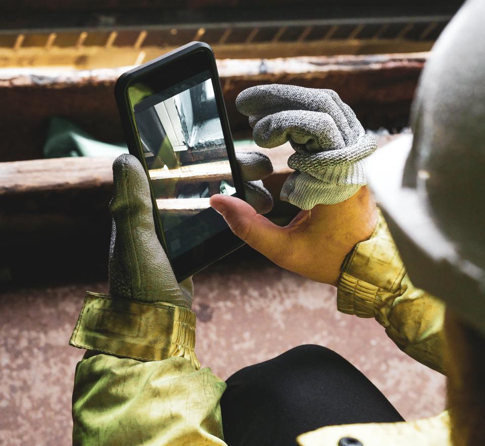 An architect holding a smartphone on a construction site.
