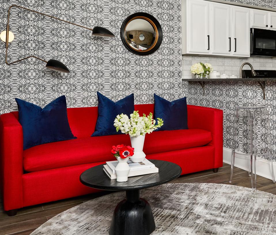 A living room with gray wallpaper and a red sofa.