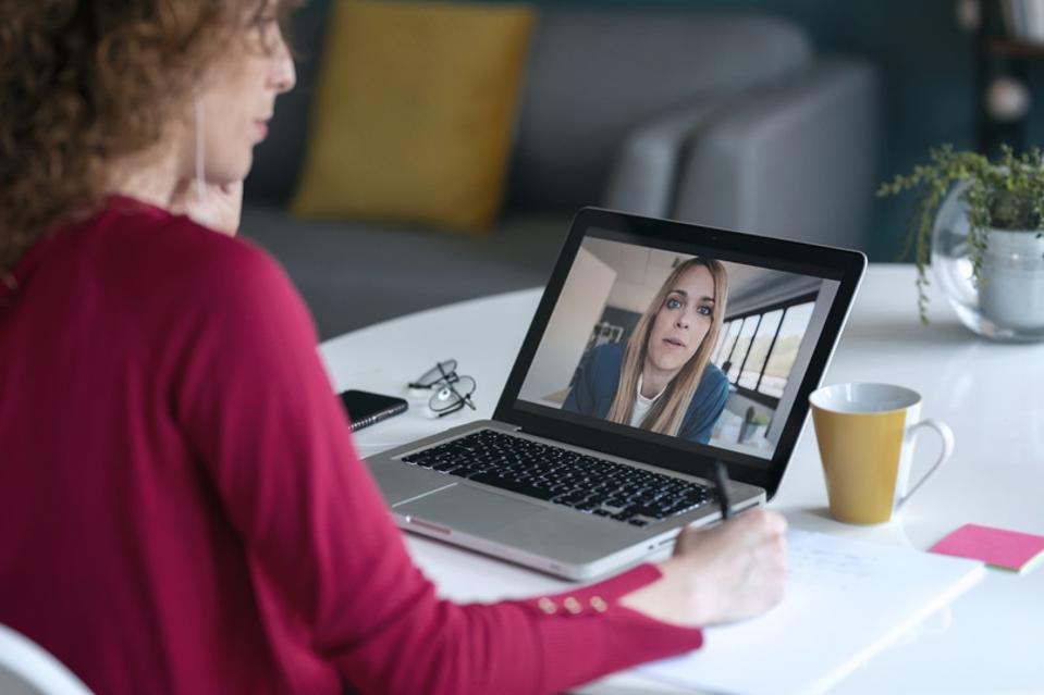 Young female entrepreneur is attending video conference through laptop at home office