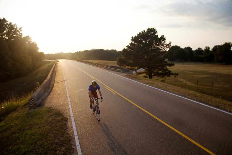 A young man, athletic and fit, rides his road bike on the sunny day, Natchez, Mississippi, USA