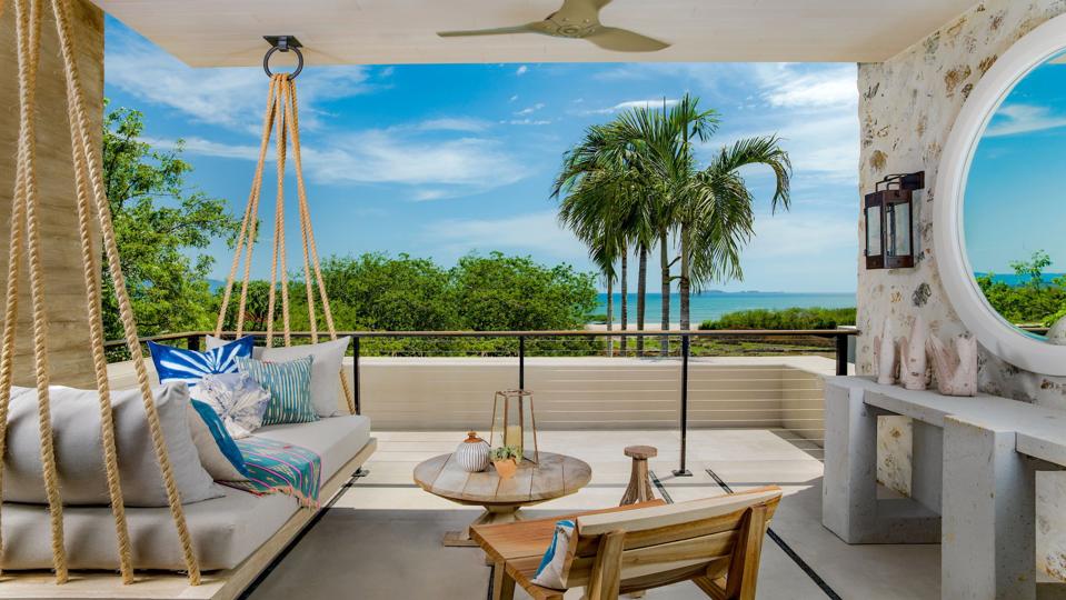 A hotel room with a swinging chair and a view of the beach