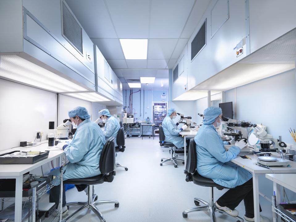 Electronics workers in clean room assembling electronic components
