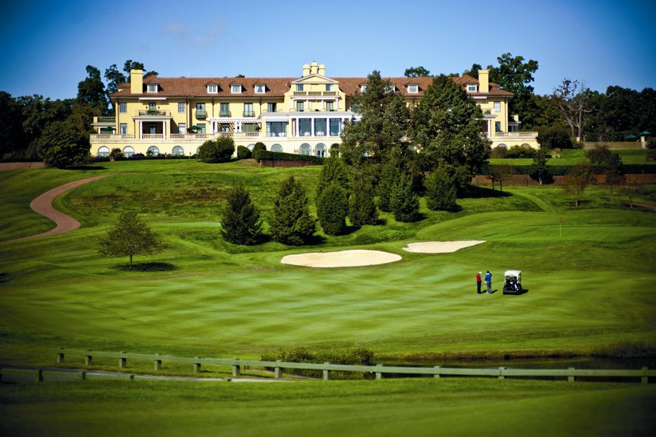 A golf course in front of a grand mansion