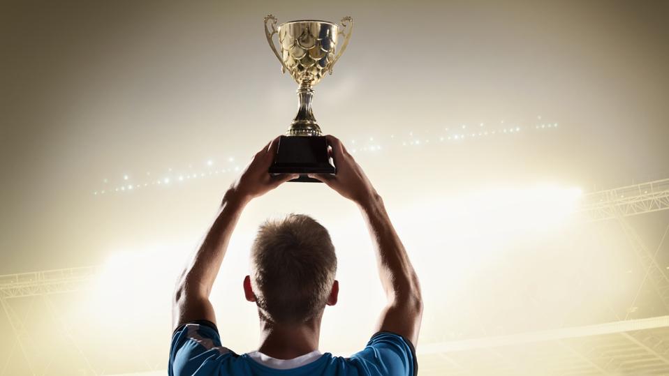 Athlete holding trophy cup above head in stadium