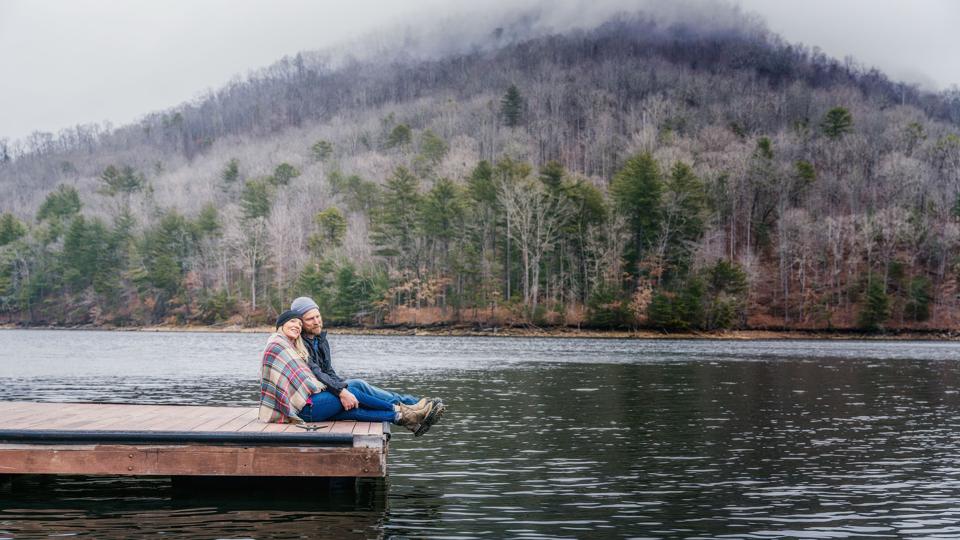 a couple sitting on a dock above a lake