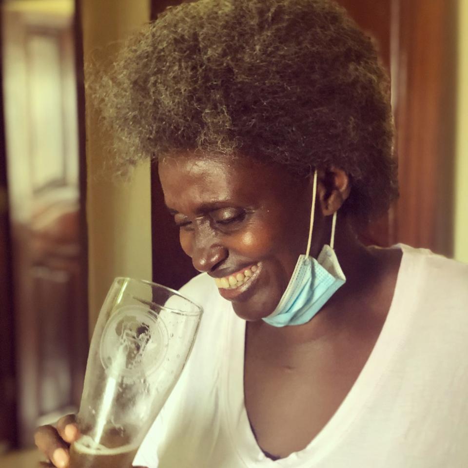 A Rwandan woman smiling holding a beer