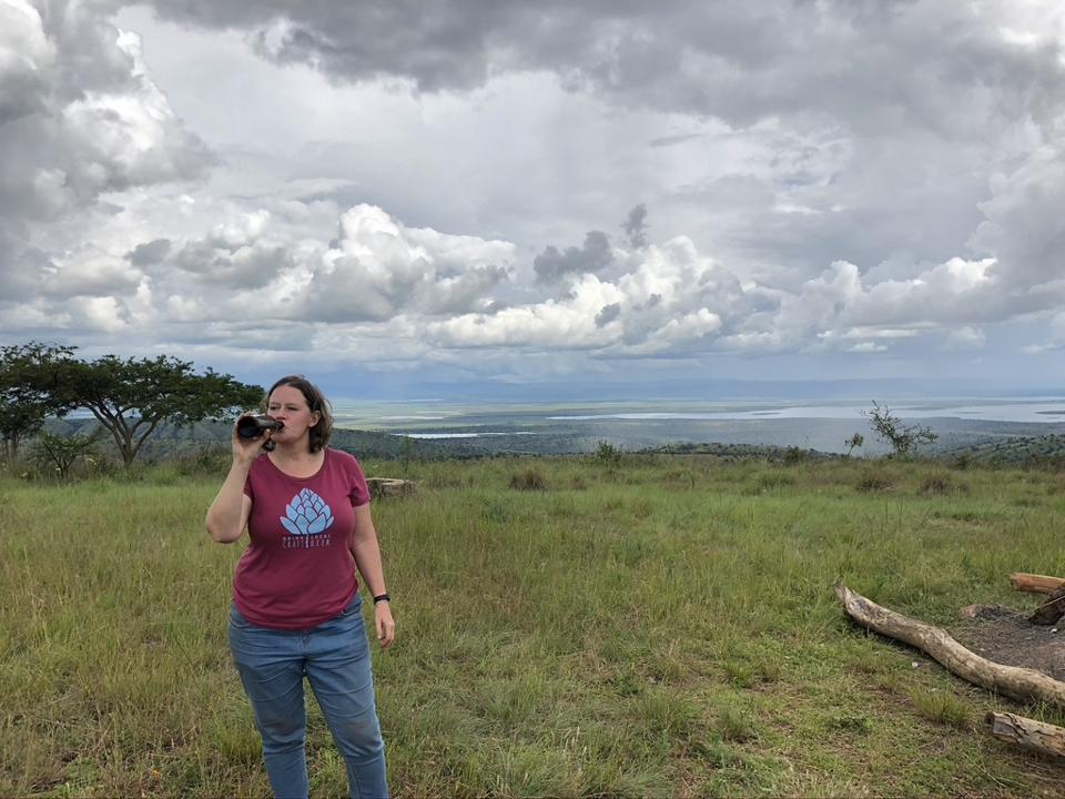 A young white woman drinking a beer in a national park in Rwanda