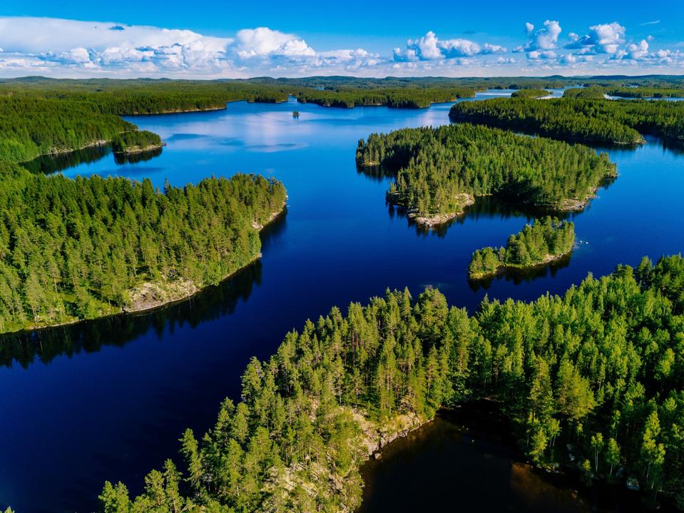 Aerial view of blue lakes and green forests on a sunny summer day in Finland.