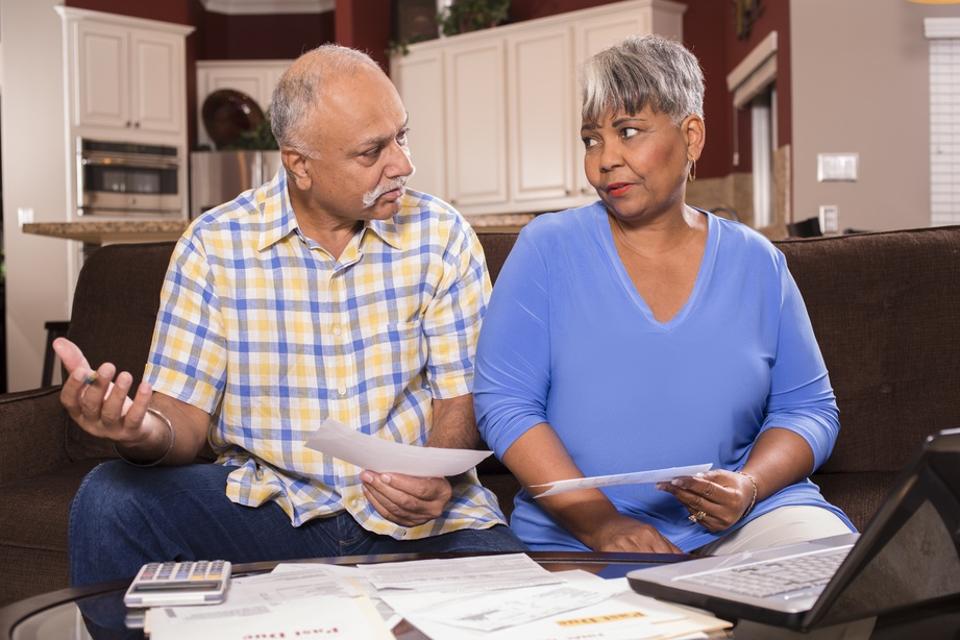 Senior couple paying monthly bills at home.