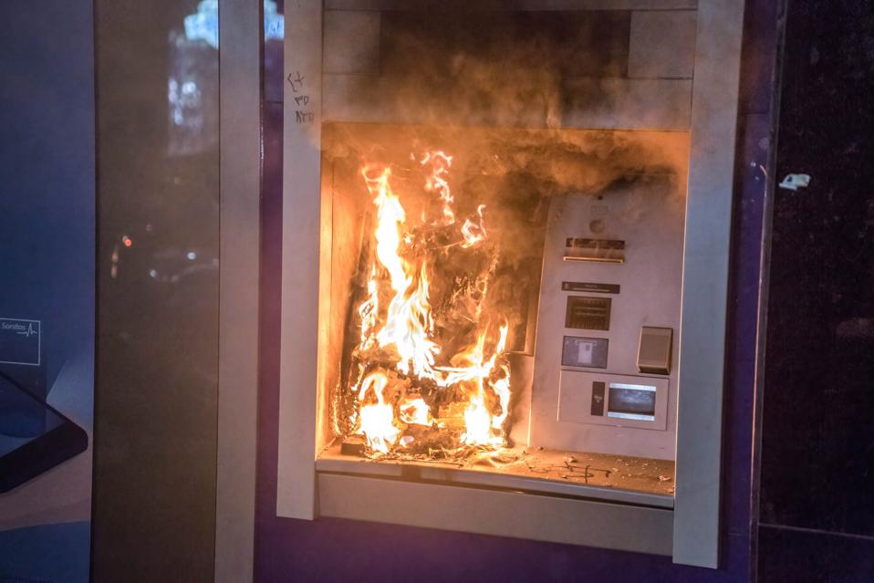 An ATM seen on fire during the demonstration. Protesters...