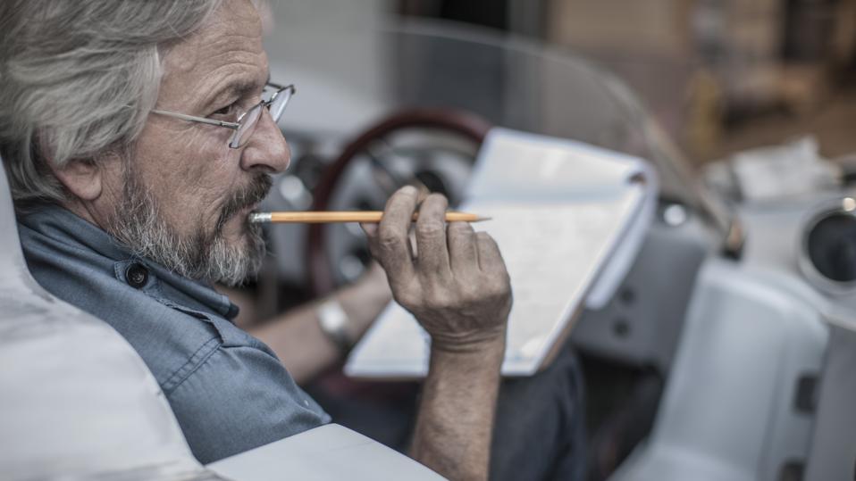Senior man with clipboard in sports car thinking