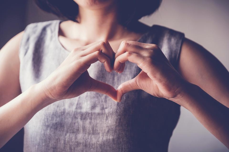 young woman making her hands in heart shape, heart health insurance, social responsibility, donation charity concept