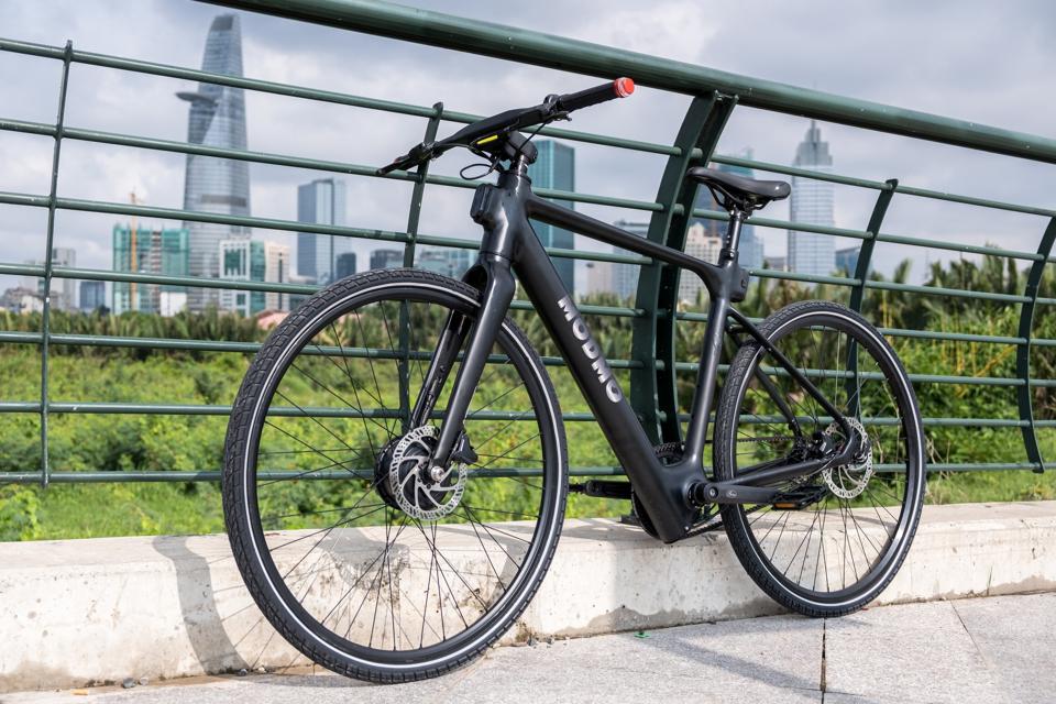 The Saigon-plus electric bicycle pictured with the Ho Chi Minh City skyline in the background.
