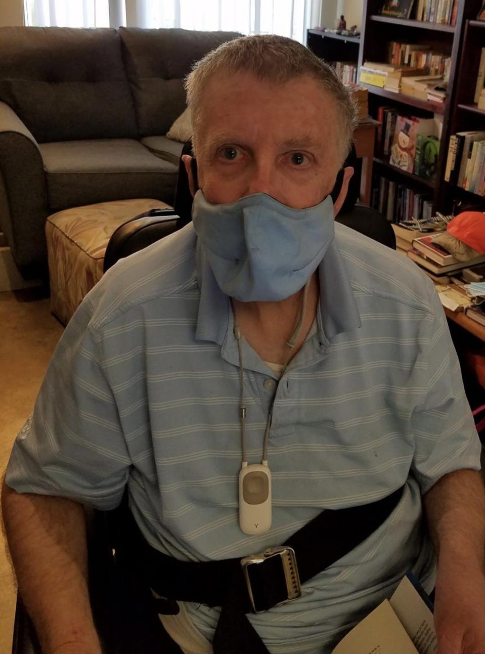 A white older man wearing a light blue face mask.