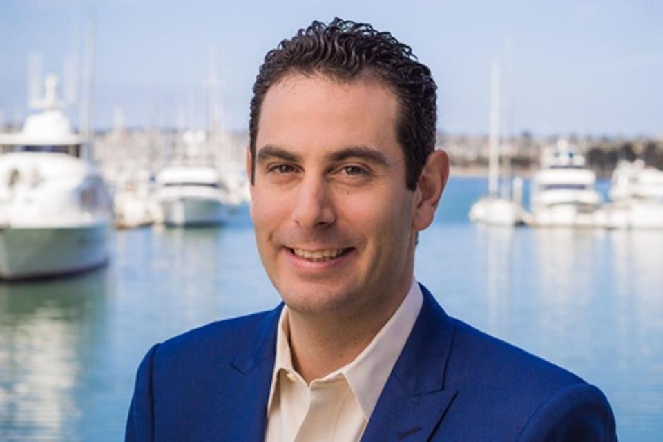 Adam Beer, GM, Lido House, an Autograph Collection property, pictured in front of the Newport Beach marina with yachts and sailboats in the background