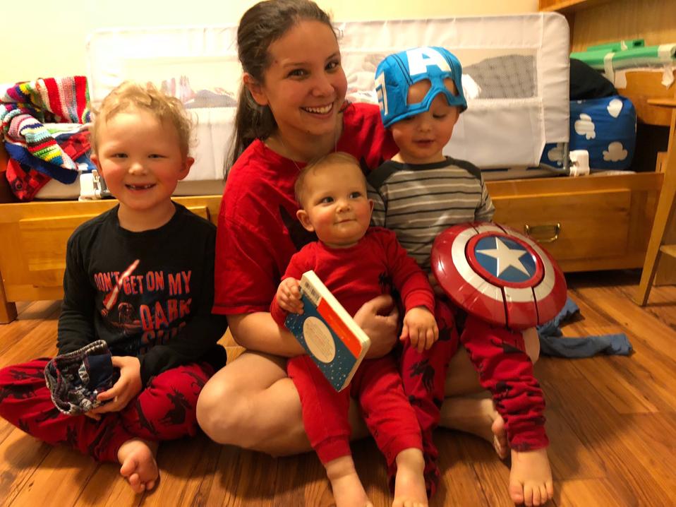 Purzner sits on the floor of a children's bedroom with three young kids in her lap.