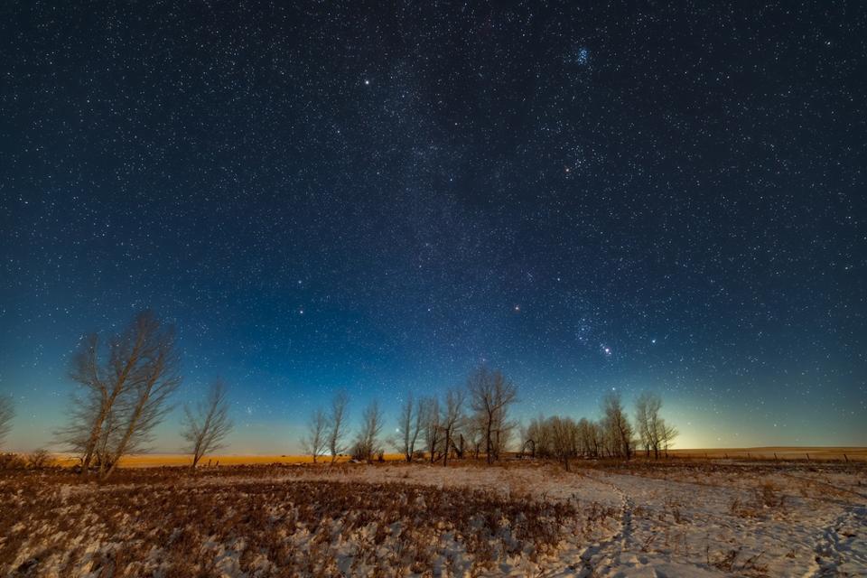 Orion and the winter stars and constellations rising in the light of a first quarter Moon on December 2, 2019. This was from home in Alberta. Orion is above the trees with Aldebaran in Taurus and the Pleiades above him. At top left is the star Capella and