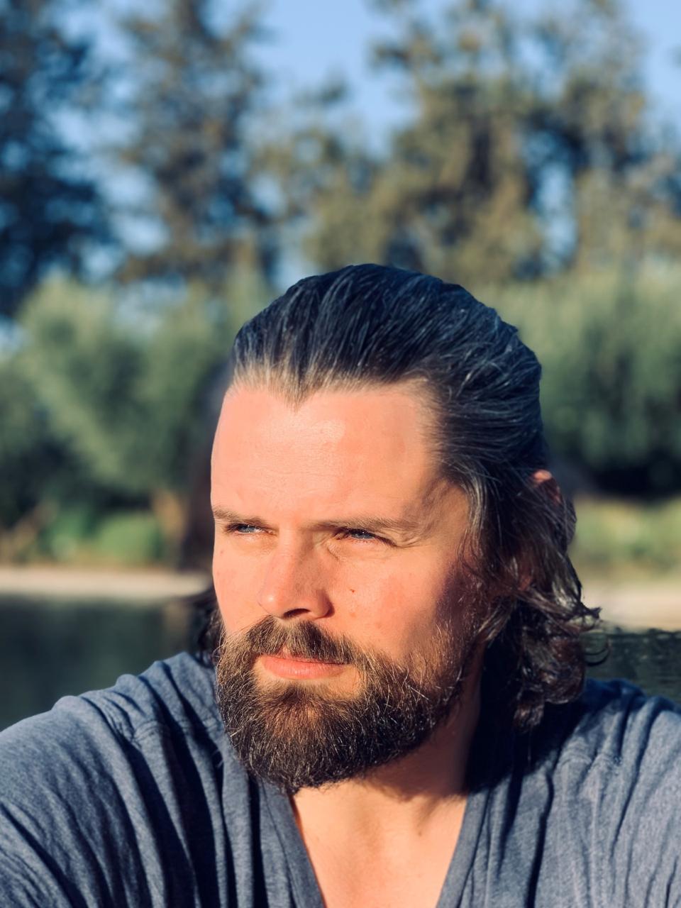 Image of man with long brown hair in a pony tail and a beard.