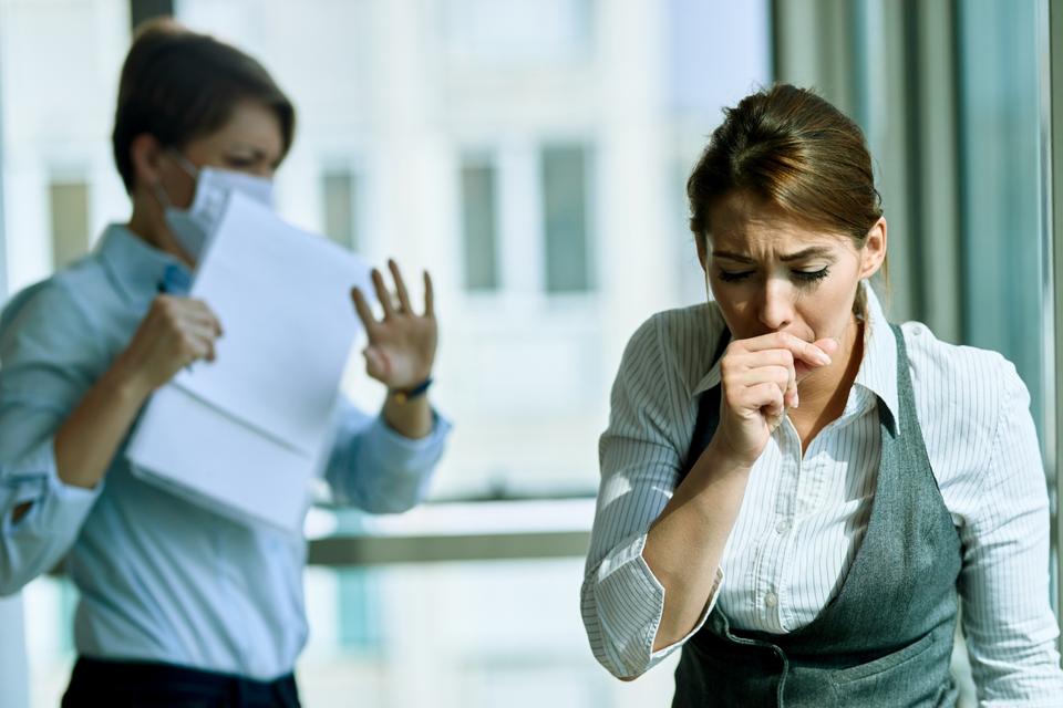 Young businesswoman coughing in the office.