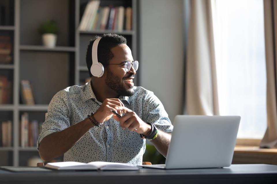 Happy businessman wearing headphones, listening to a podcast