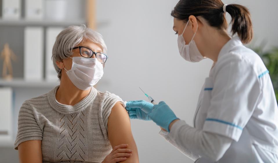 Doctor giving a senior woman a vaccination