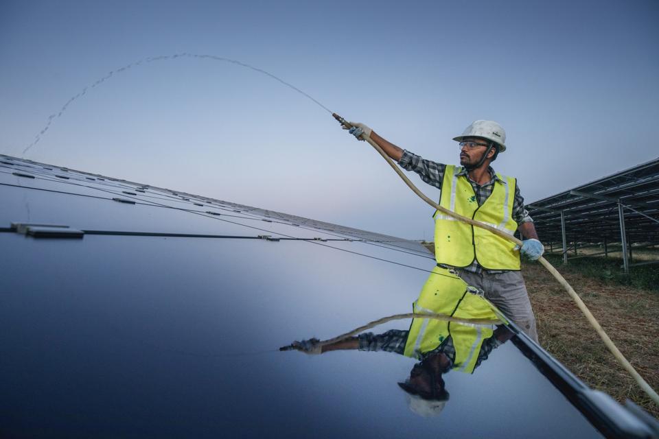 A worker is cleaning solar panels at the Fortum solar park...