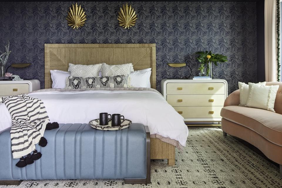 A bedroom with blue wallpaper and a rug