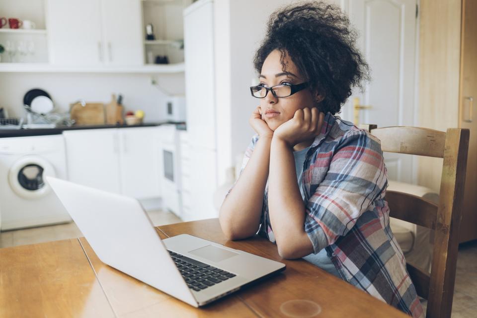 Pensive woman using laptop at home