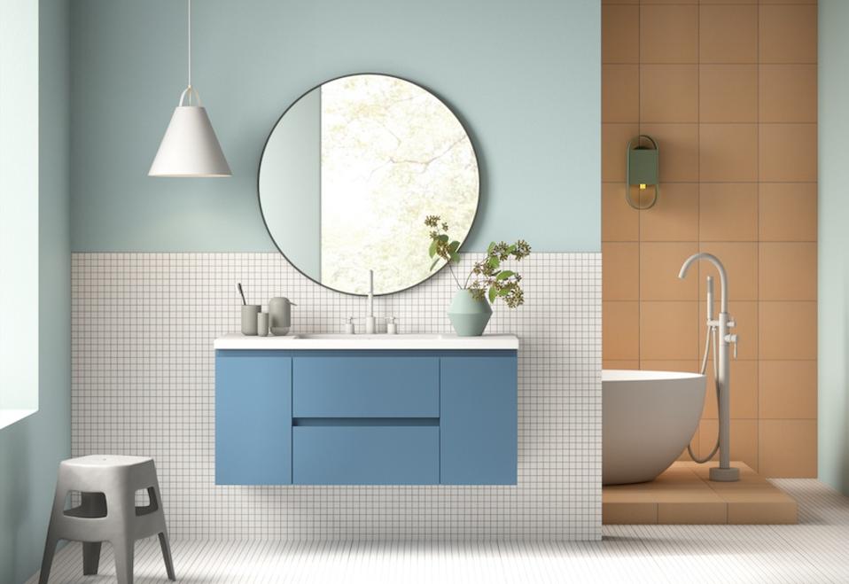 a bathroom with blue cabinetry and a round mirror