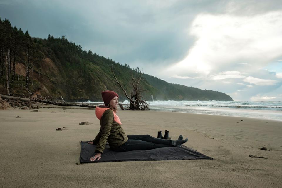 woman sitting on travel blanket on the beach