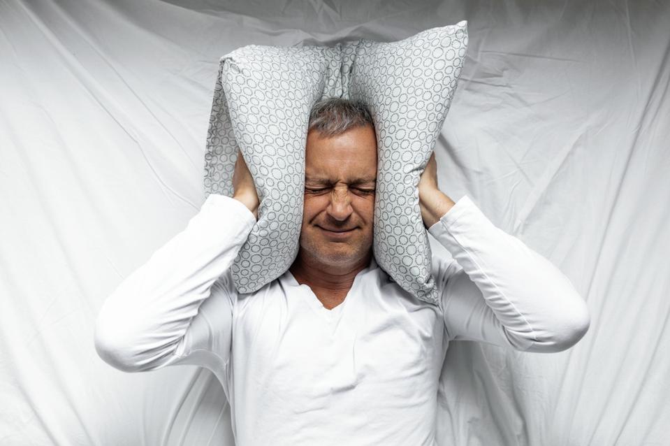 Man trying to sleep covering ears