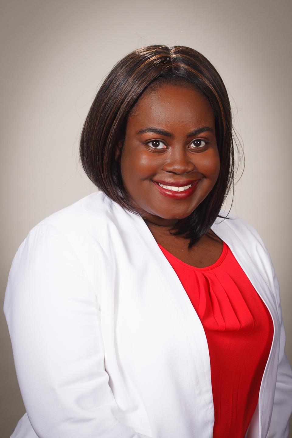 Jasmin Crentsil smiling in a white blazer and red shirt.