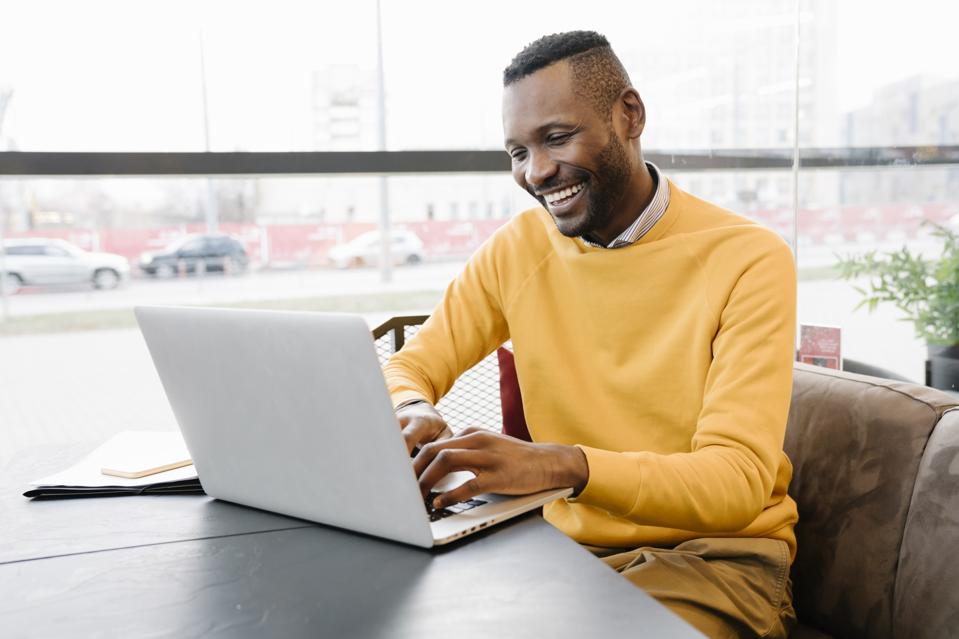 Happy man using laptop in a cafe