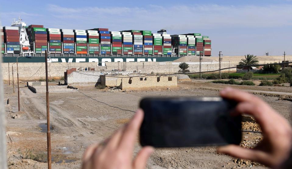 An Egyptian woman takes photos of Evergreen's Ever Given container ship after being fully dislodged from the banks of the Suez Canal on Monday. The vessel, a megaship the length of four football fields, was refloated and the Suez Canal reopened to traffic in the afternoon.