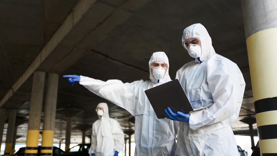 Men in special virus protective suits making research of coronavirus availability