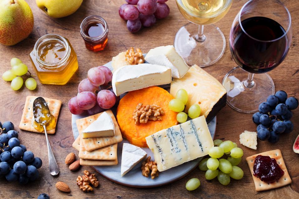 Assortment of French cheese, grapes with red and white wine.