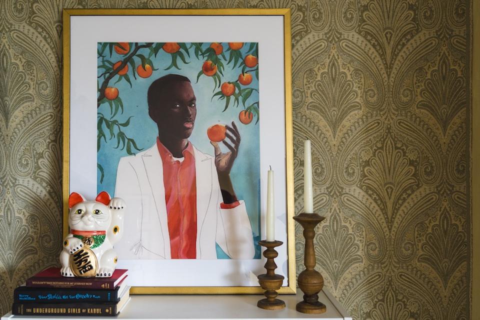 A print of a black man eating an orange on top of a shelf.