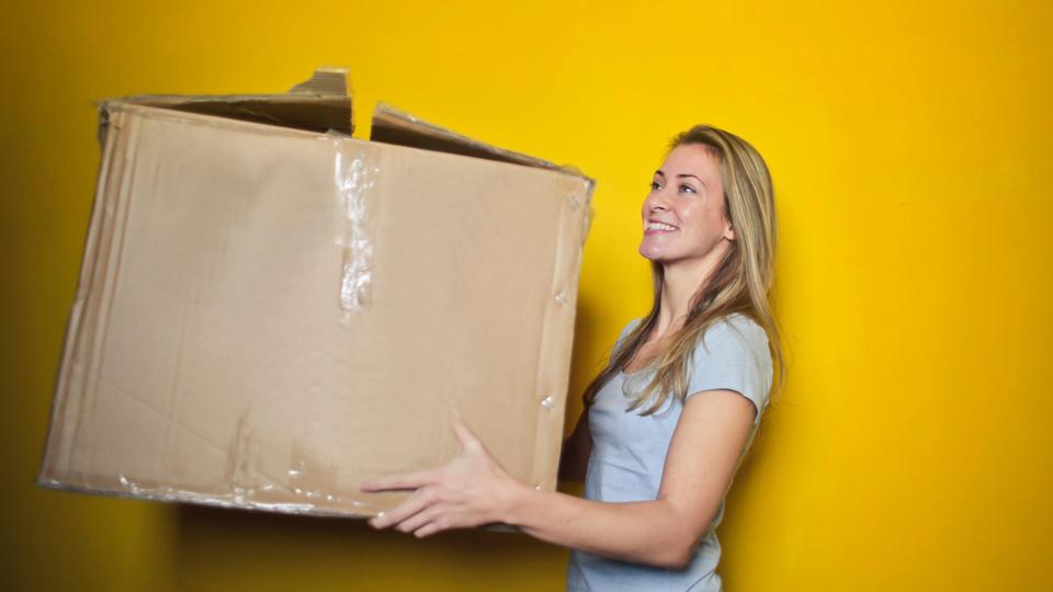 Woman carrying cardboard box, smiling