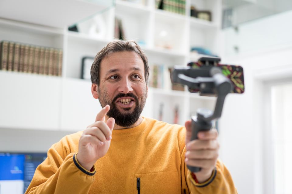 Handsome bearded man making video with smartphone indoors