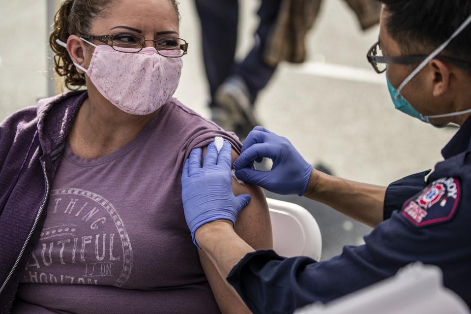 A woman gets her COVID-19 vaccine from a paramedic.