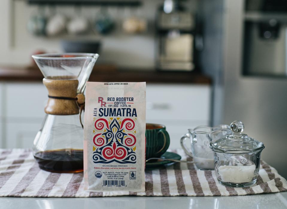 Bag of coffee and coffee brewing carafe on a kitchen table.