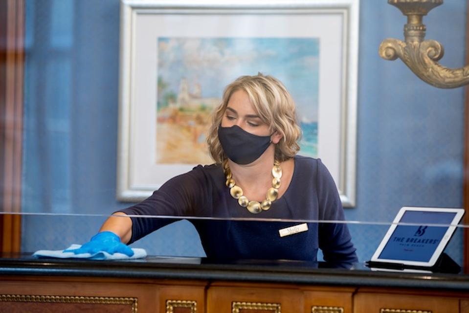 Guest and employee. health and safety are front and center at The Breakers; Front desk receptionist cleaning her station