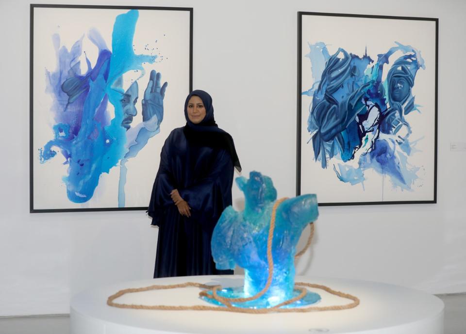 Muna Al-Bader standing in front of her gallery pieces.