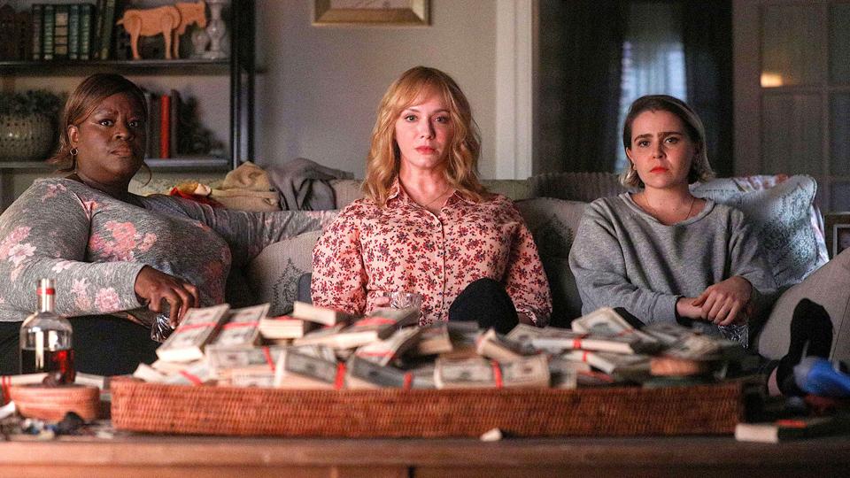 Beth, Annie and Ruby sit on a couch with lots of money