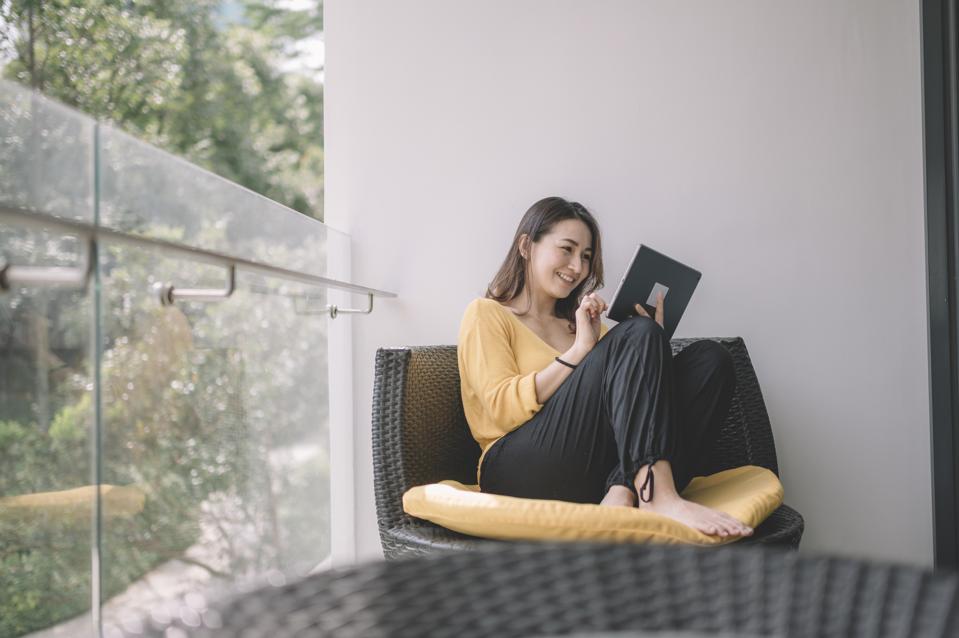 an asian chinese beautiful woman surf the net with her digital tablet in the afternoon at her balcony