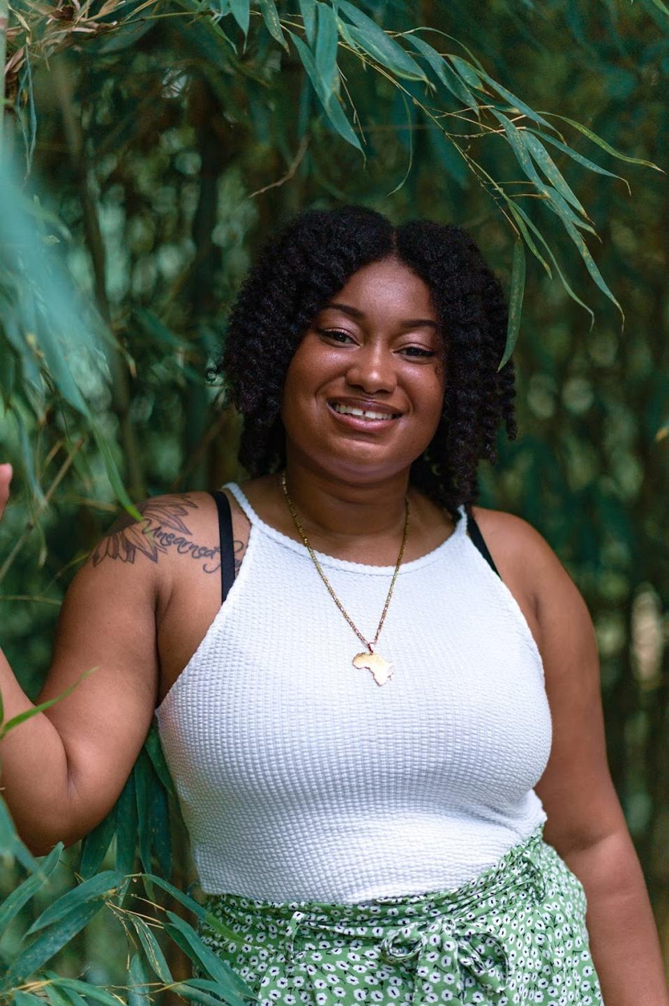 Alishia McCullough smiling with a white shirt and green bottom in a forest.